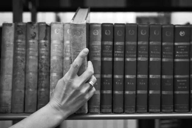 Hand taking a book from a bookshelf. Photo