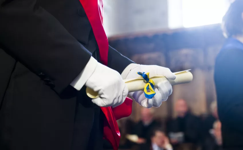 A person holding a degree diploma. Photo.