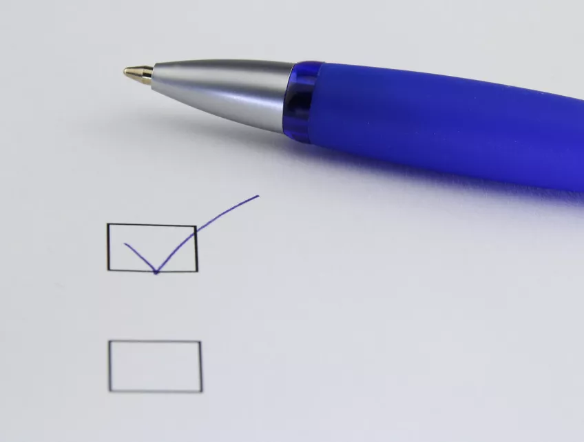 A pen and some checkboxes on a piece of paper. Photo.