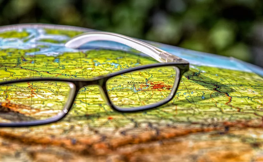 A pair of glasses atop a world map. Photo.