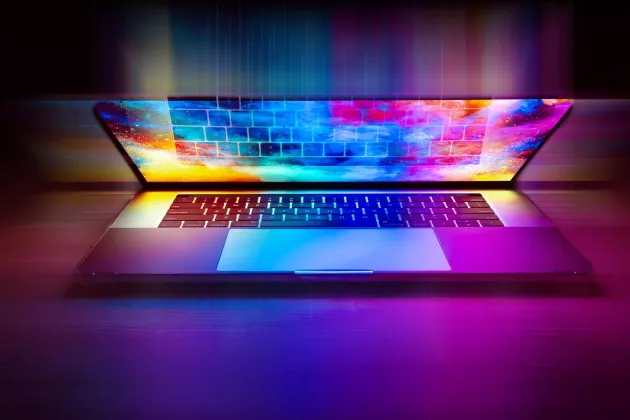 Laptop med ljussken i olika färger. Foto.