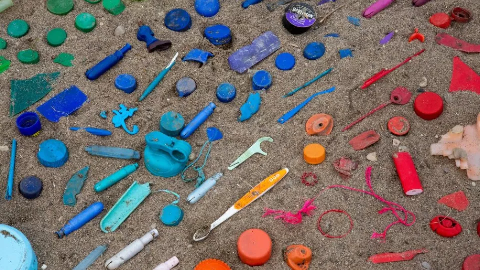 Plastsaker sorterade efter färgskala på en sandstrand