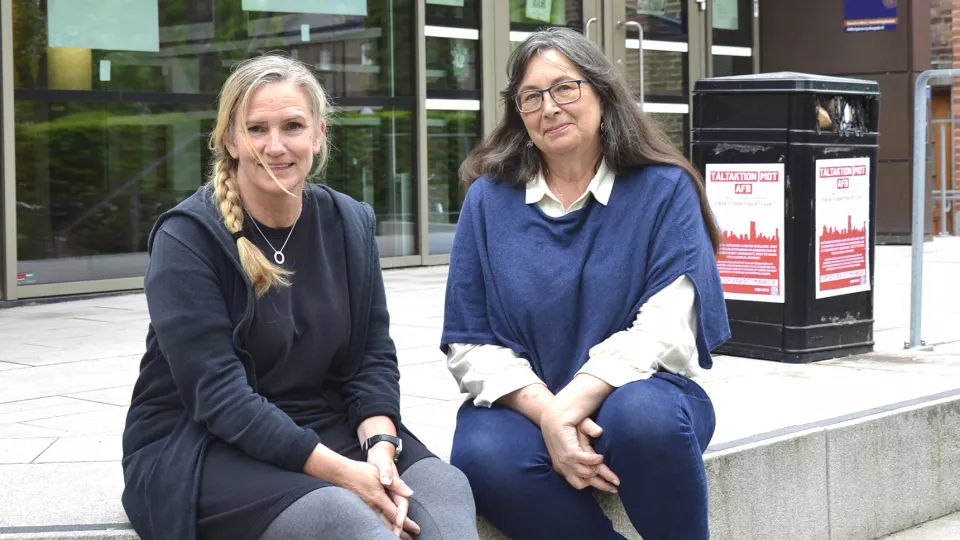 Foto på Katarina Jacobsson och Kerstin Svensson som sitter på trappan framför Socialhögskolan. Foto.