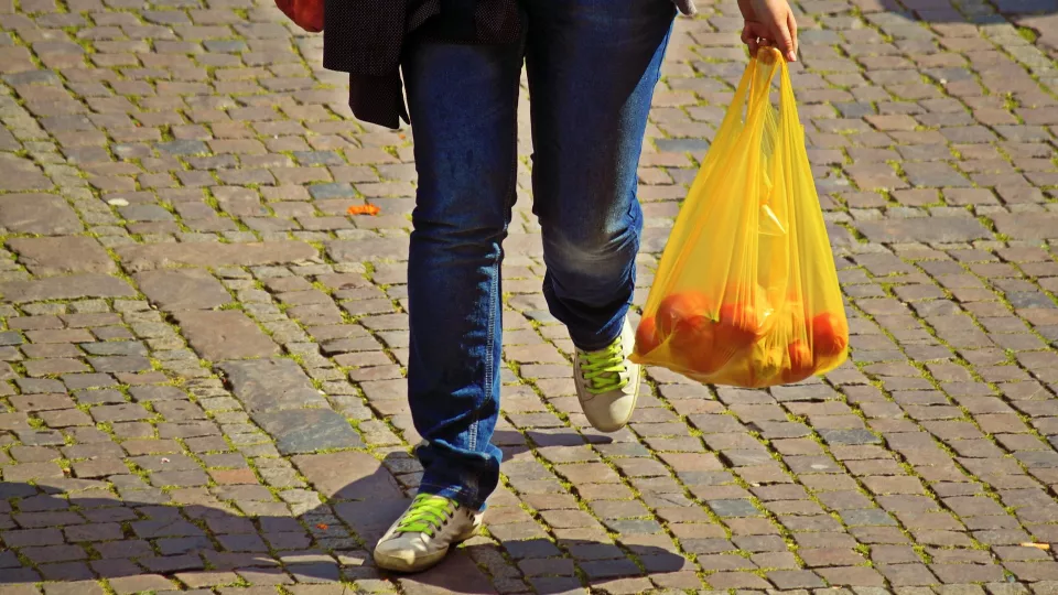En person går med en plastpåse i handen. Foto.
