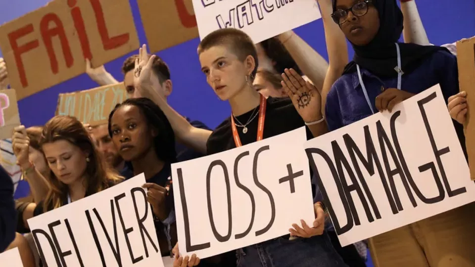 Foto från COP27. Ett antal personer står med plakat i händerna med texten "Deliver Loss + Damage".