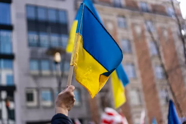Ukrainska flaggan framför ett höghus. Foto.