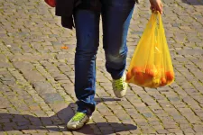 En person går med en plastpåse i handen. Foto.