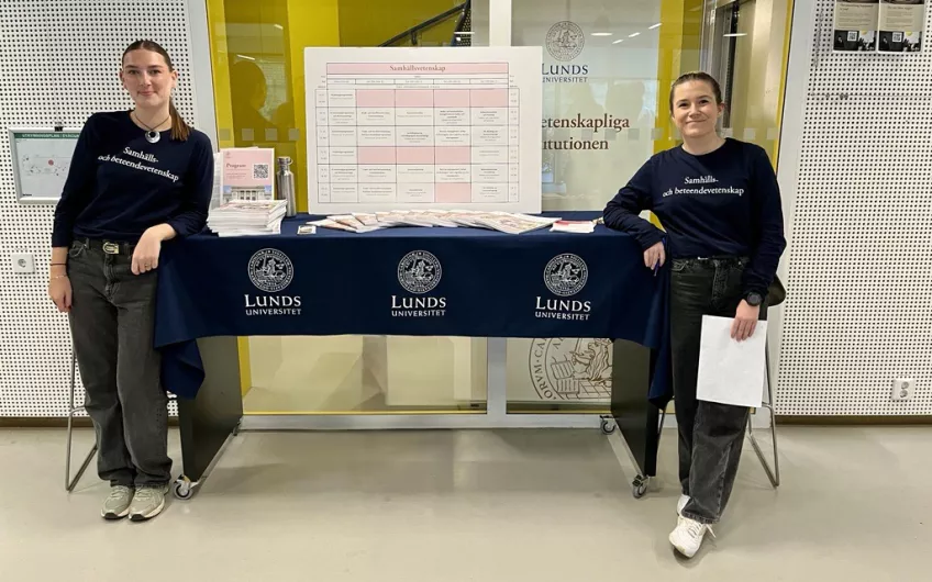 Två studenter står vid ett bord. Foto. 
